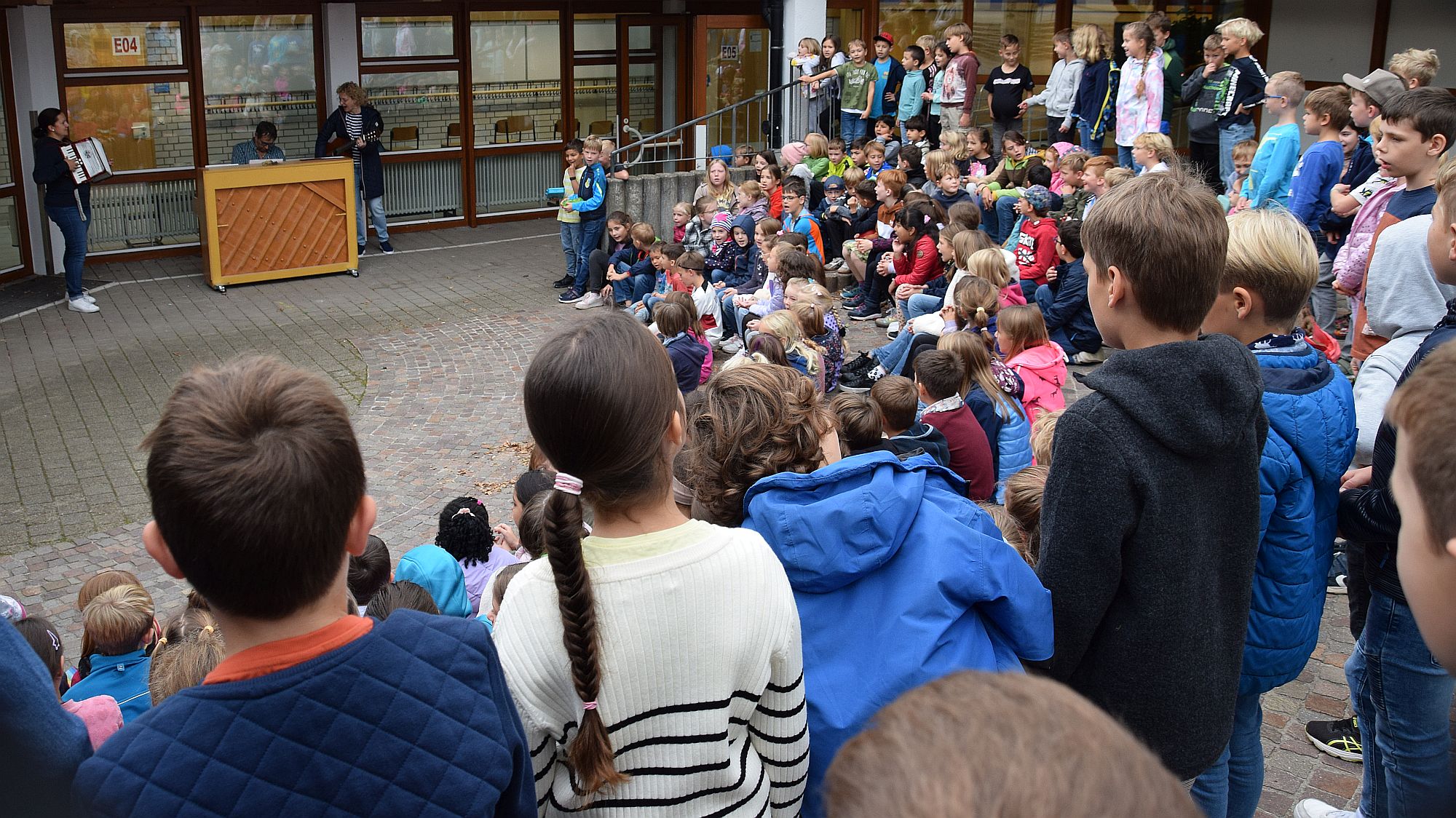 Kinder im Schulhof singen Herbstlieder